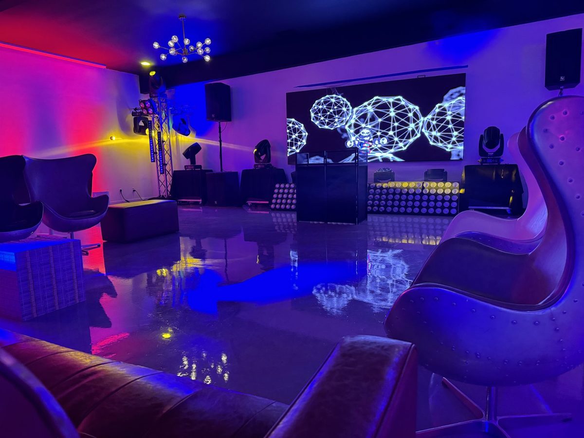 Lounge with curved seating, DJ booth, LED wall and purple and blue lighting