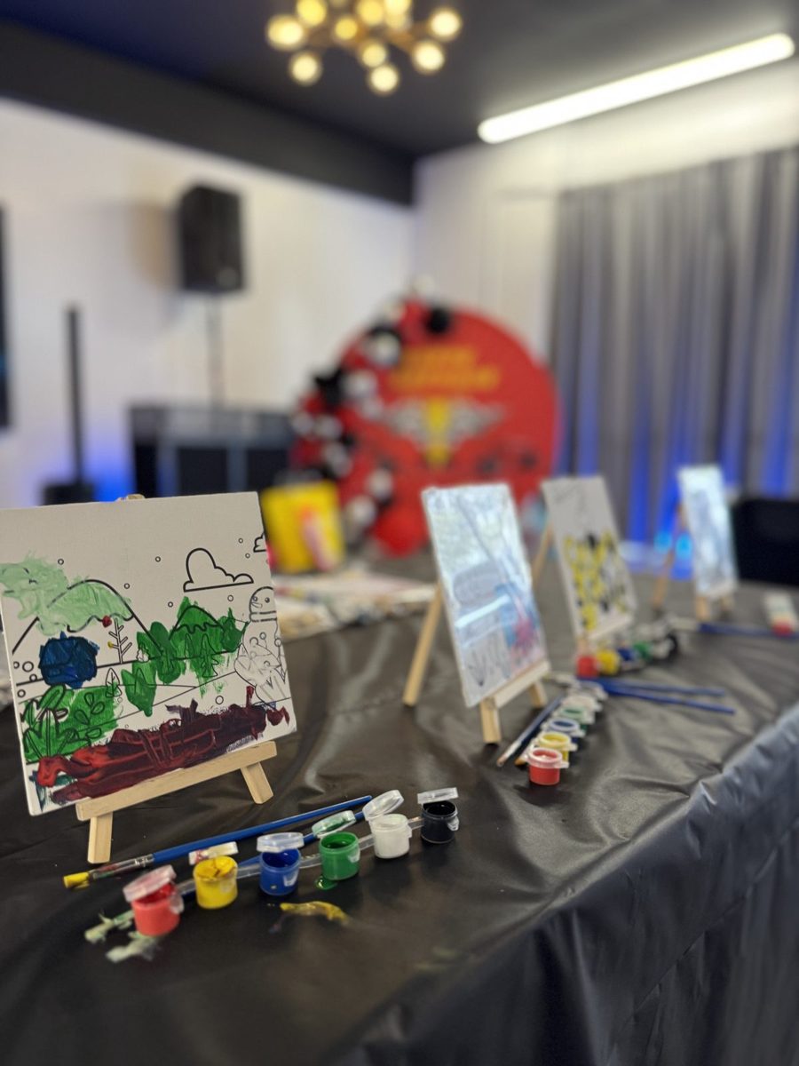 Kids painting party table with small canvases on easels and paint cups on a black tablecloth