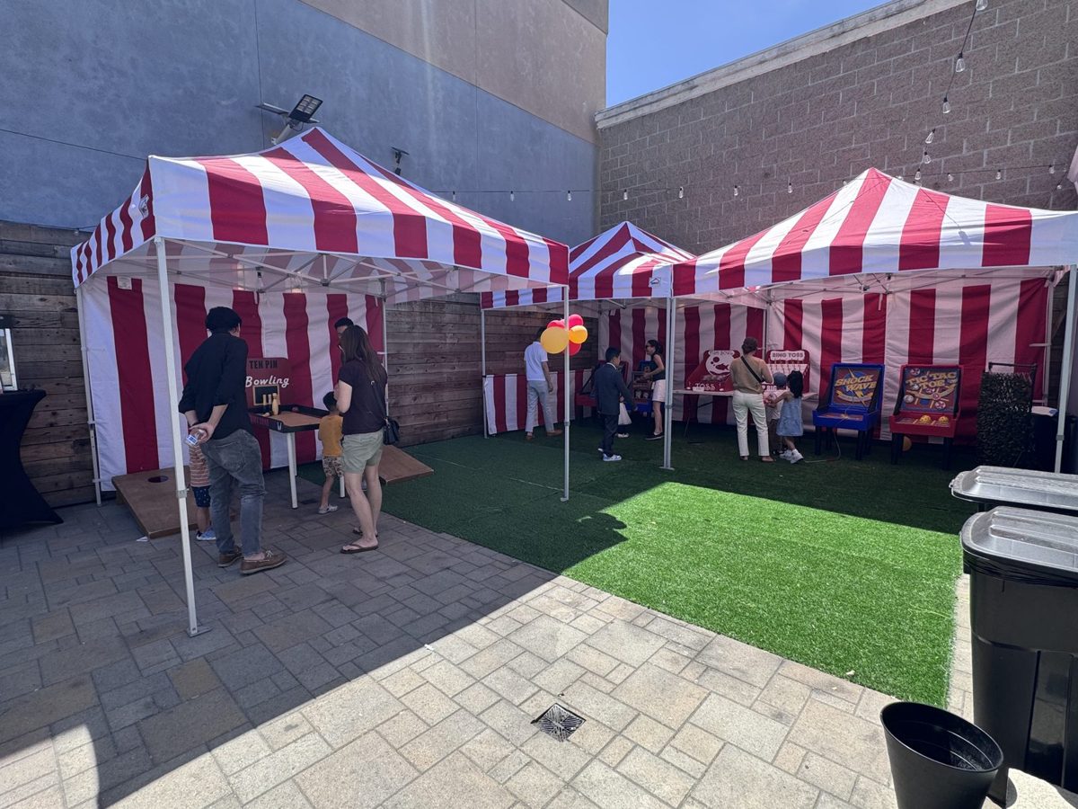 Courtyard set up as a carnival with red and white striped game tents on turf